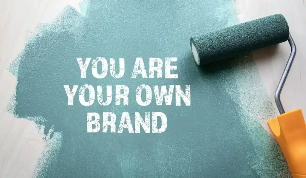 Flatlay image of paint roller with teal pain with words "You Are Your Own Brand" on top.