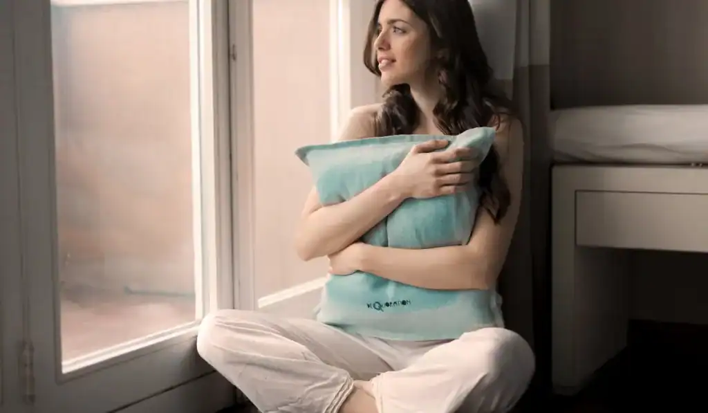 Woman by window holding green pillow